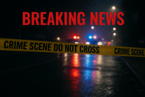 Breaking News scene showing wet city street at night blocked by yellow crime scene tape, with police cars and flashing lights in the distance.