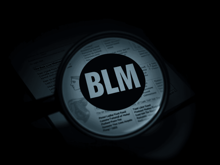 Magnifying glass highlighting the letters “BLM” on a dark background, symbolizing federal scrutiny and investigation into alleged Black Lives Matter financial misconduct.