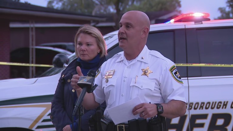 Hillsborough County Sheriff Chad Chronister speaking at a press briefing after the Brandon hostage standoff, with an HCSO patrol SUV in the background.