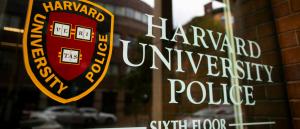 Harvard University Police Department headquarters window with the official shield and lettering reflected on a Cambridge building facade.