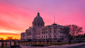 Minnesota State Capitol building in St. Paul photographed at dusk with warm lighting, used to illustrate oversight and fraud allegations involving state agencies.