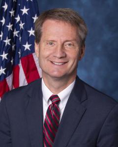 Official portrait of Rep. Tim Burchett standing in front of an American flag.