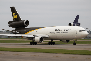 UPS and FedEx MD-11 cargo planes grounded on tarmac under cloudy skies after Kentucky crash.